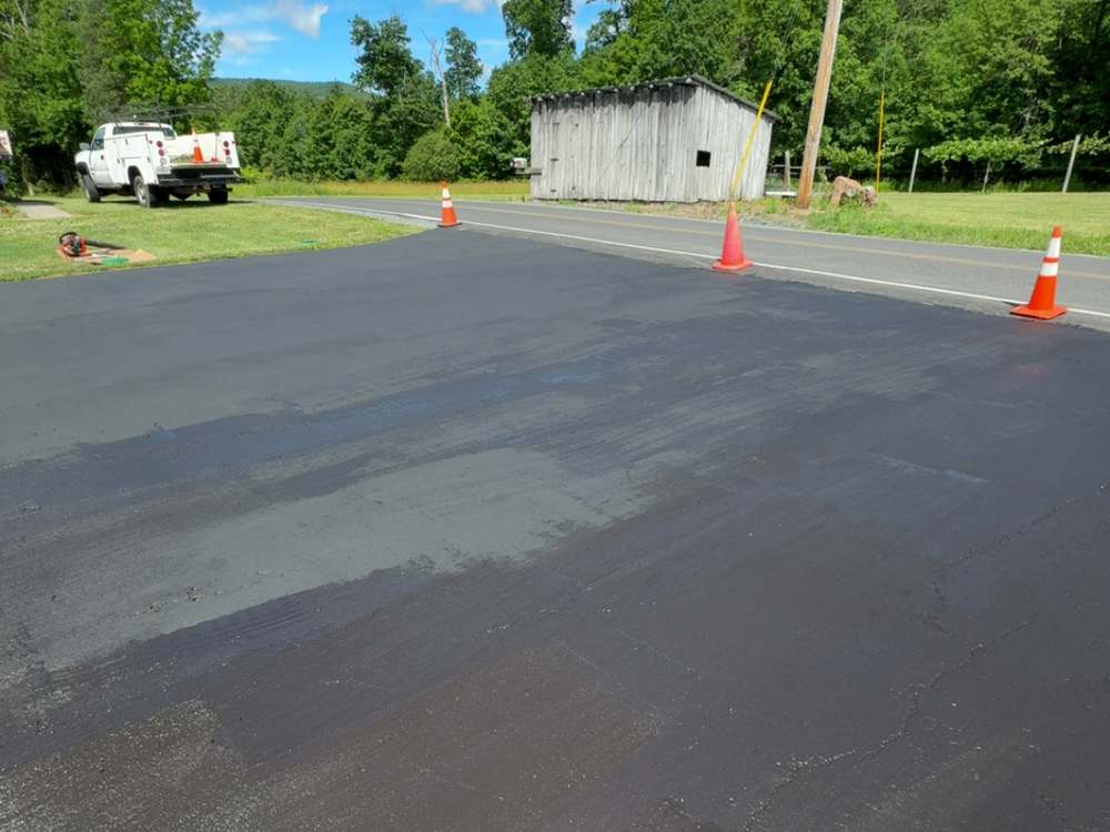 Freshly seal coated asphalt driveway, still wet, coned off